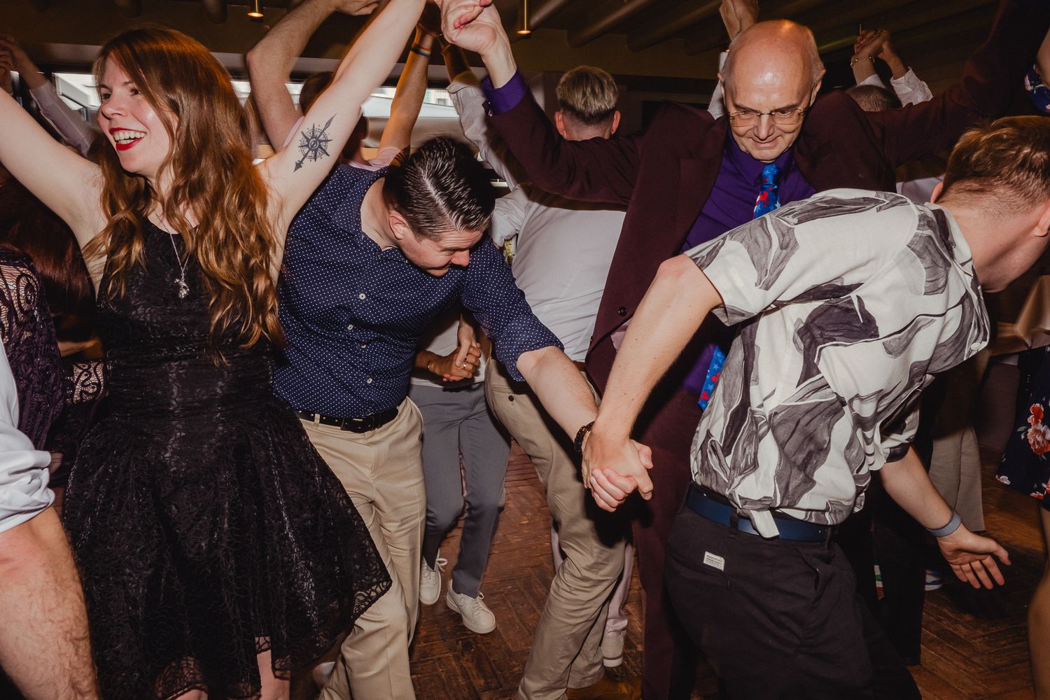 People dancing and celebrating at a lively party or reception with a dark indoor setting.