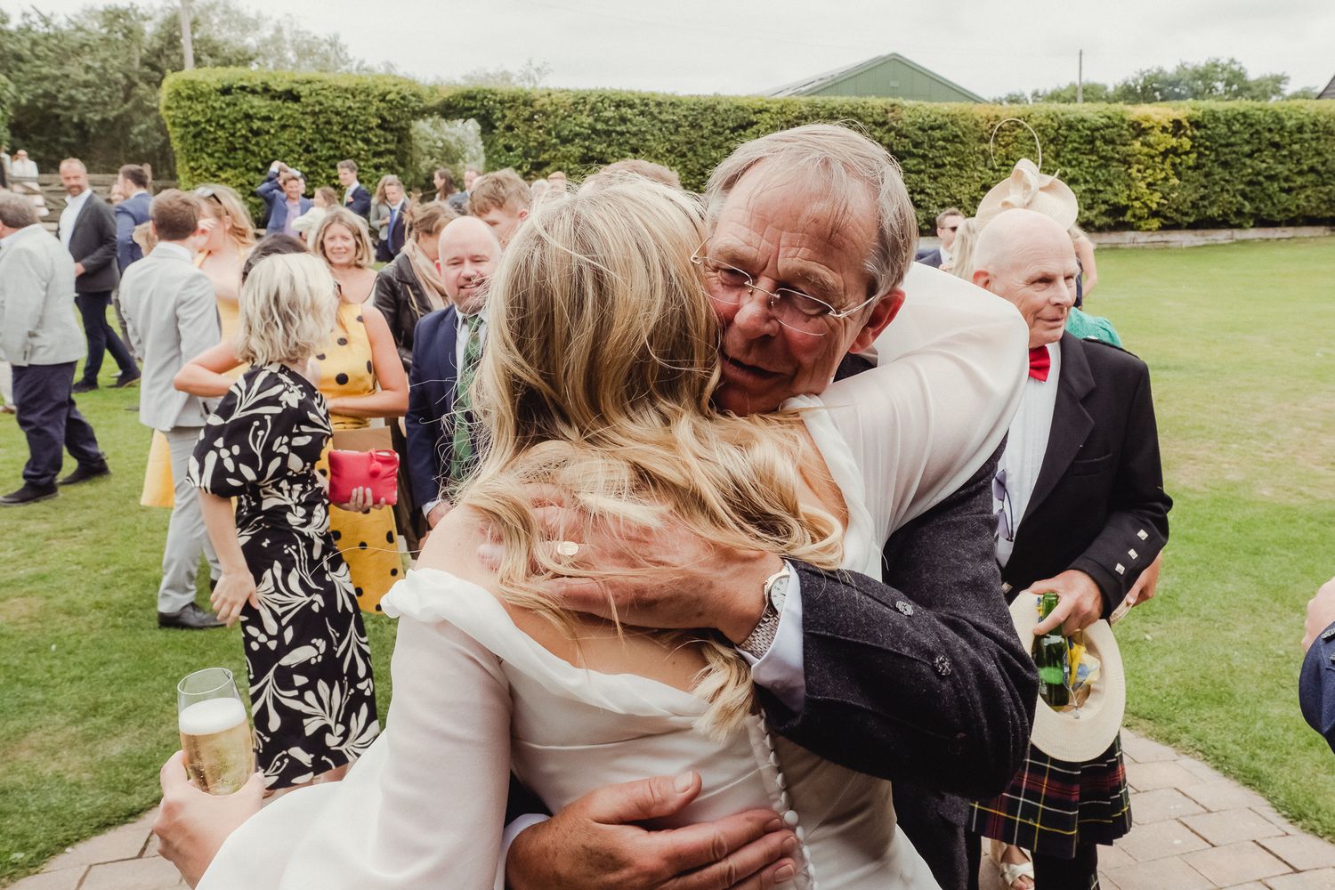 Wedding guests celebrate with hugs and warm embraces during an outdoor garden reception.