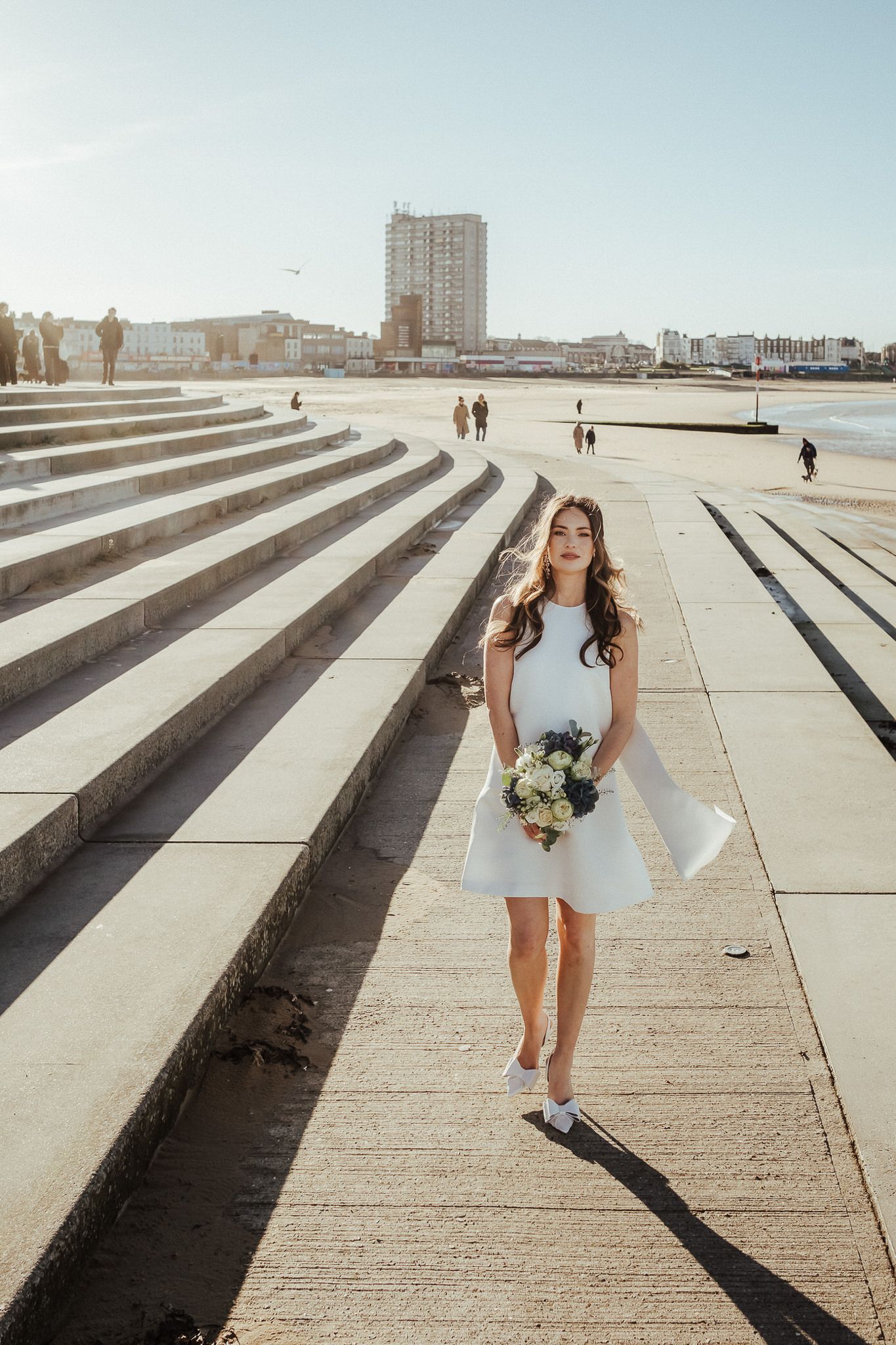 A series of photos showing a person in a light blue dress posing on concrete steps with a cityscape backdrop.