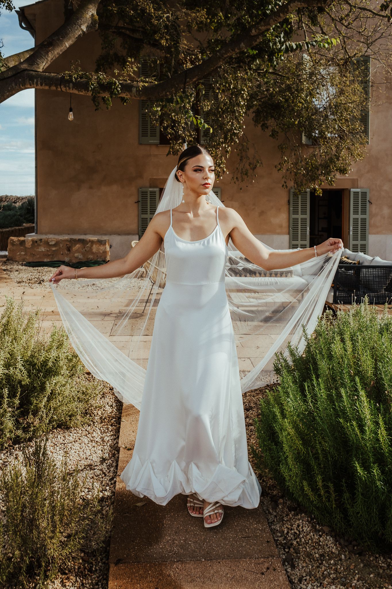 A flowing white wedding dress swirls gracefully in motion against a rustic adobe building and desert landscaping.