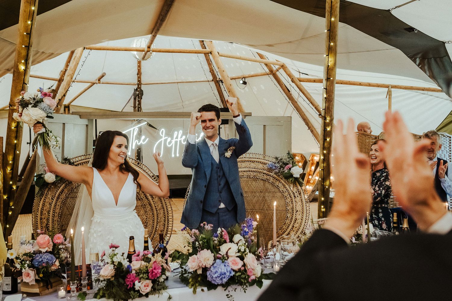 Wedding reception panorama inside a beautifully decorated tent with warm lighting and festive atmosphere.