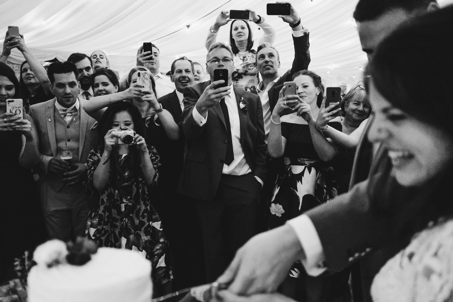 Wedding guests capture photos during a celebratory moment at the reception.