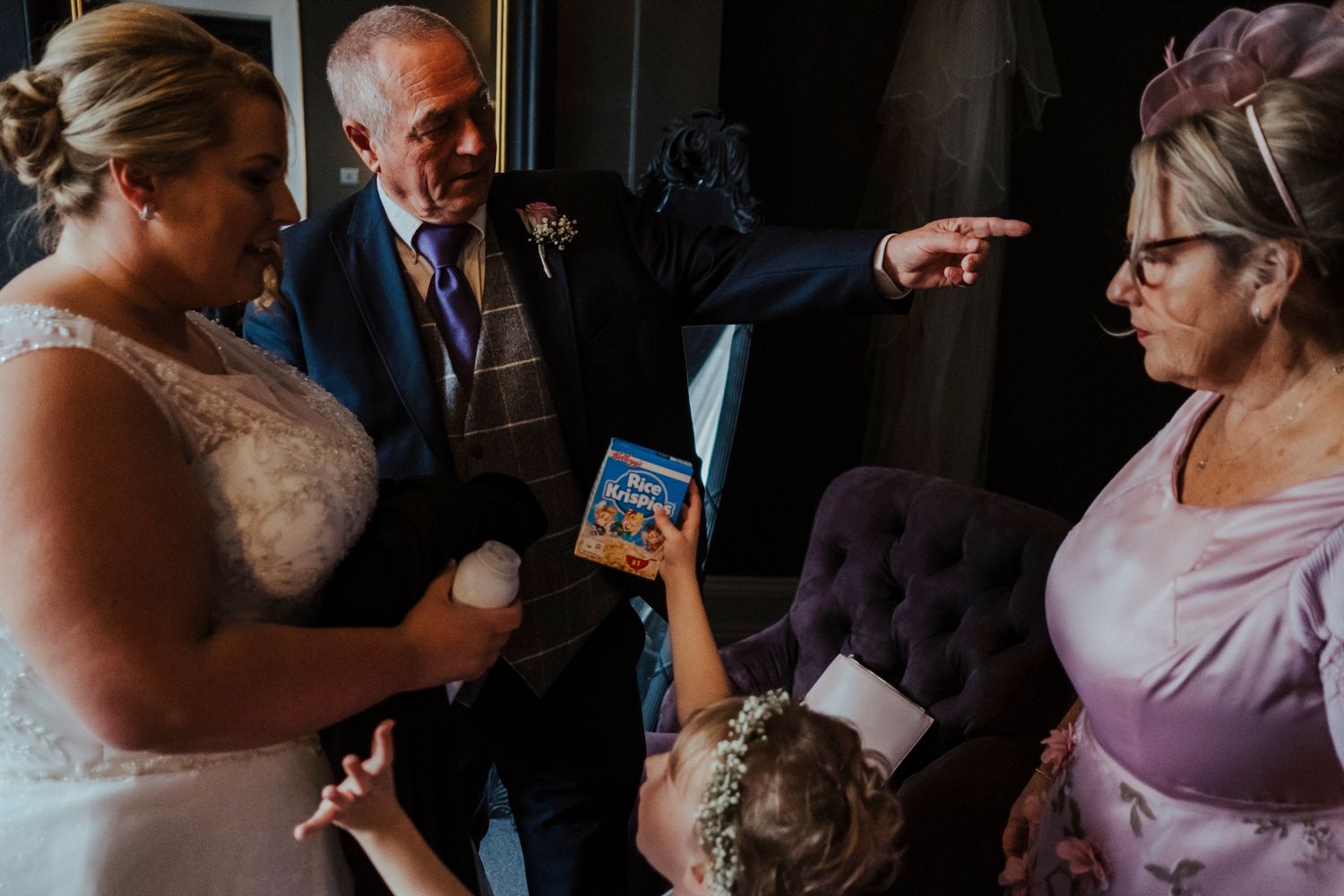 Wedding party members gathered around looking at something on a mobile device.