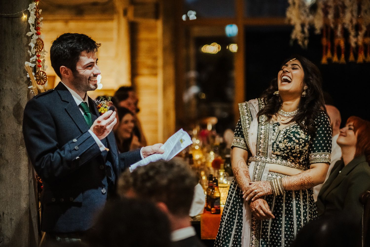A couple shares an energetic moment of laughter during a wedding reception.