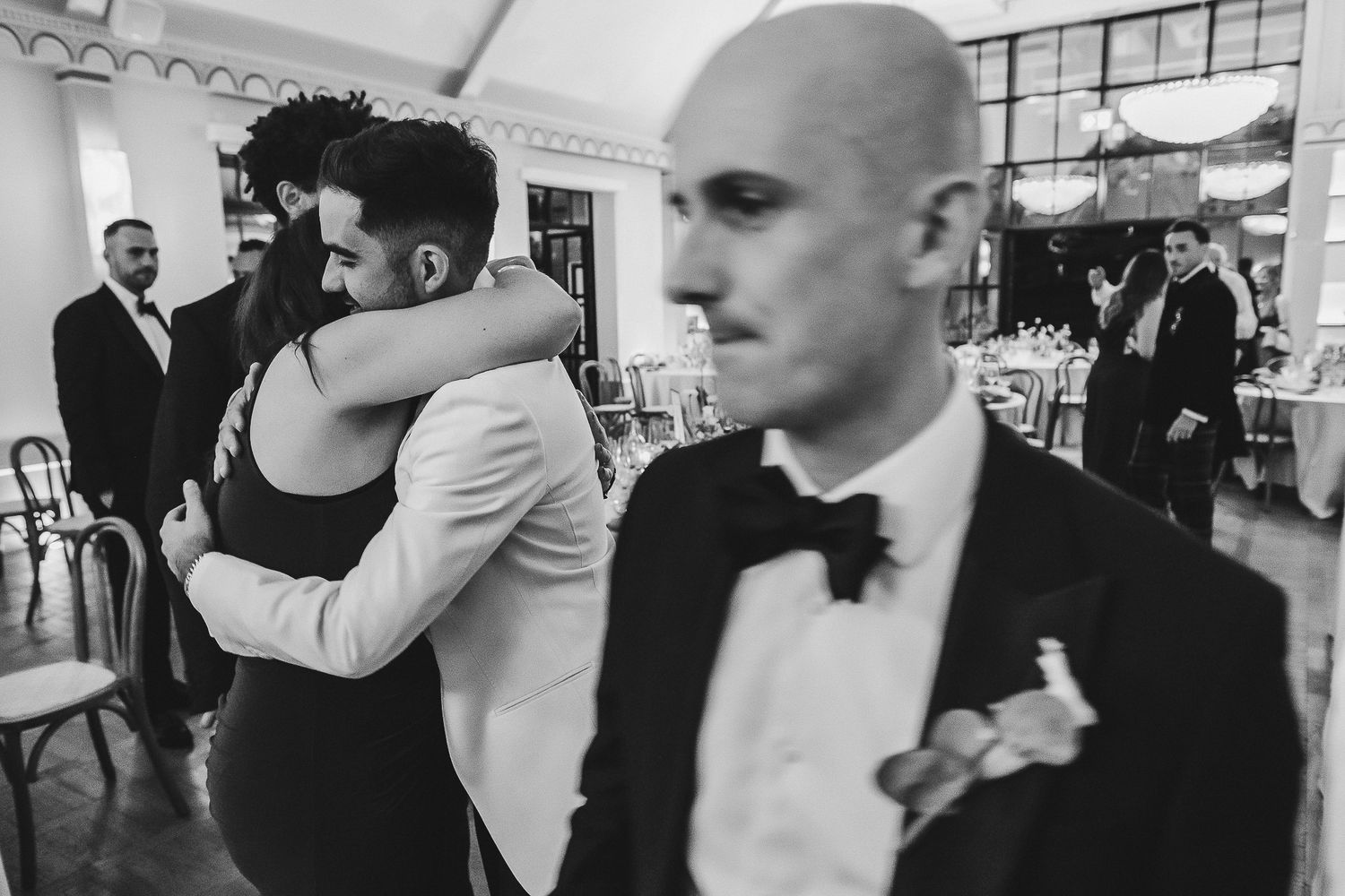 A black and white photo collage showing intimate moments at a wedding reception with people embracing and dancing.