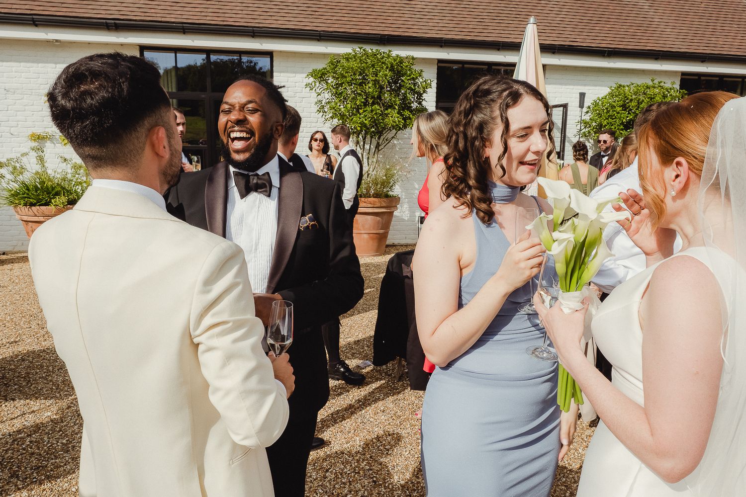 Wedding guests gather and celebrate at an outdoor reception venue with brown roofing.