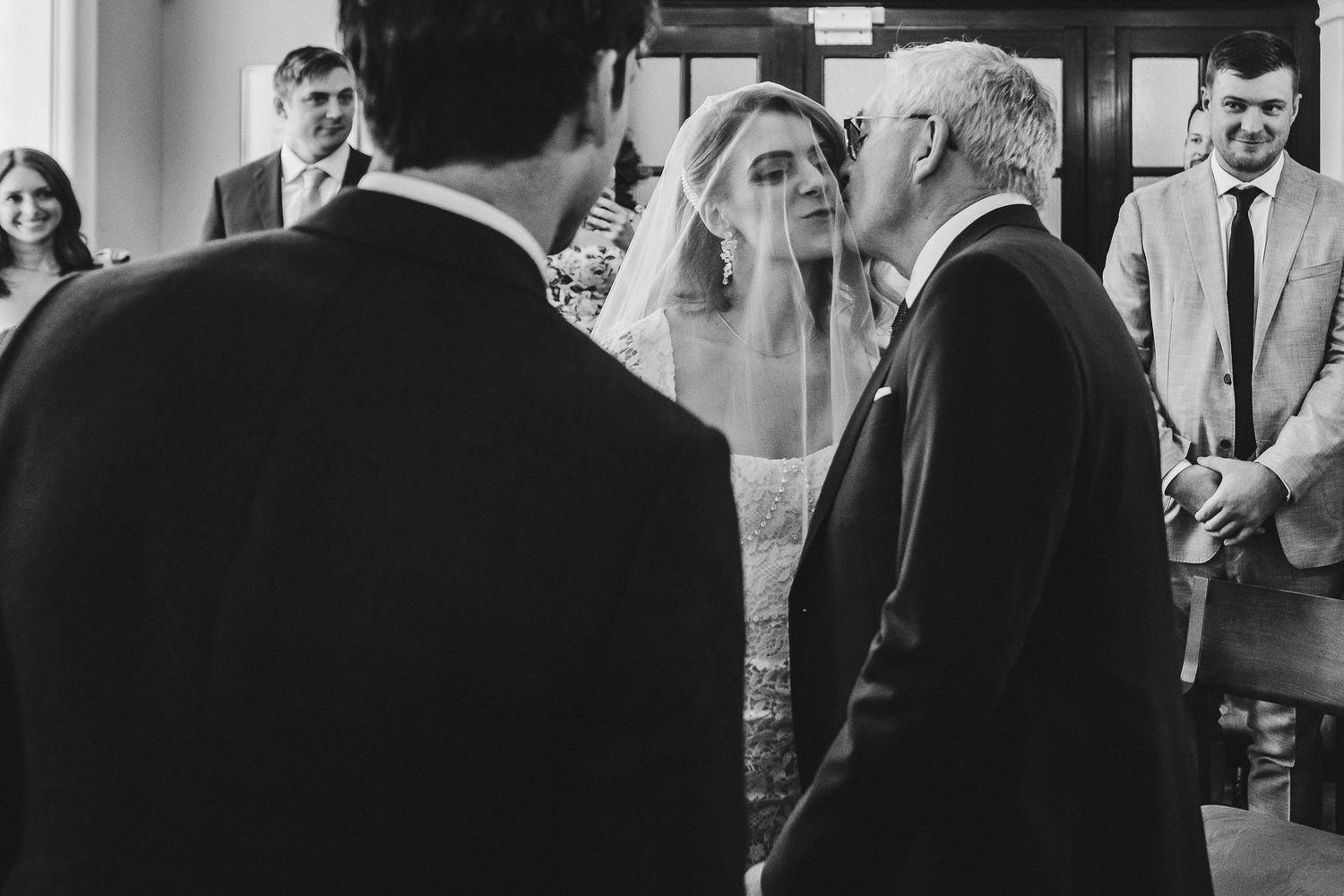 A black and white photograph shows people gathered in a hallway during what appears to be a professional event.