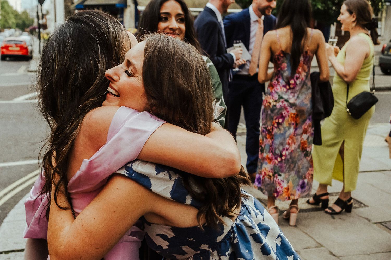 Wedding guests sharing emotional hugs and embraces outside a venue.