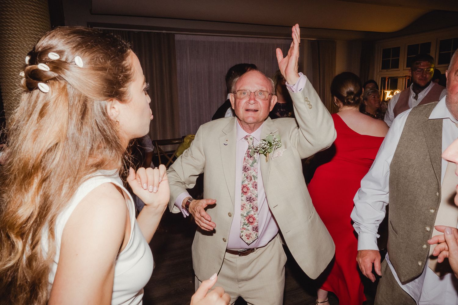 Wedding guests dance and celebrate at an indoor reception venue with joyful energy.
