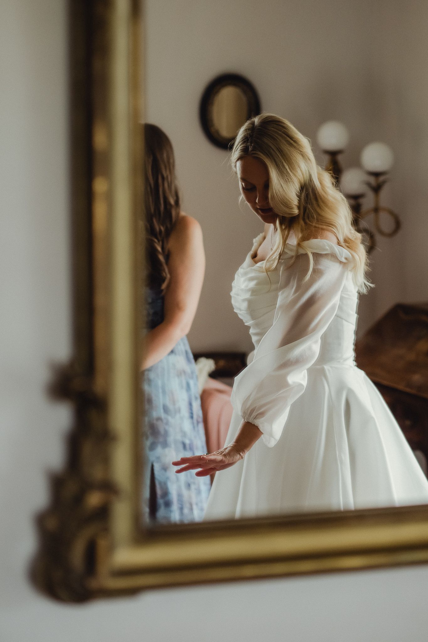 A person in a white wedding dress spins and twirls in front of an ornate gold mirror in a soft-focus photo series.
