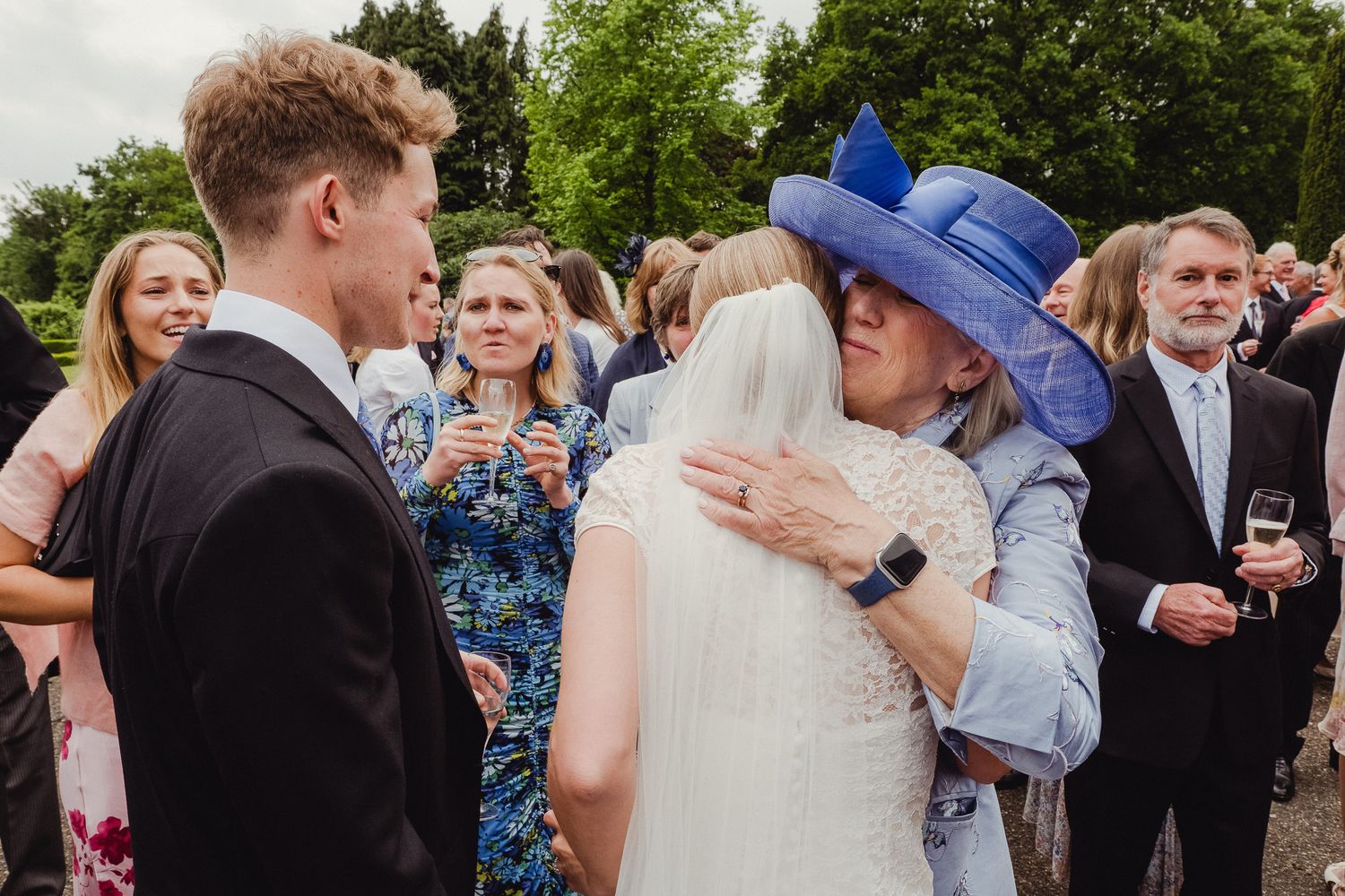 Wedding guests gather outside in a garden setting, celebrating during a festive outdoor reception.