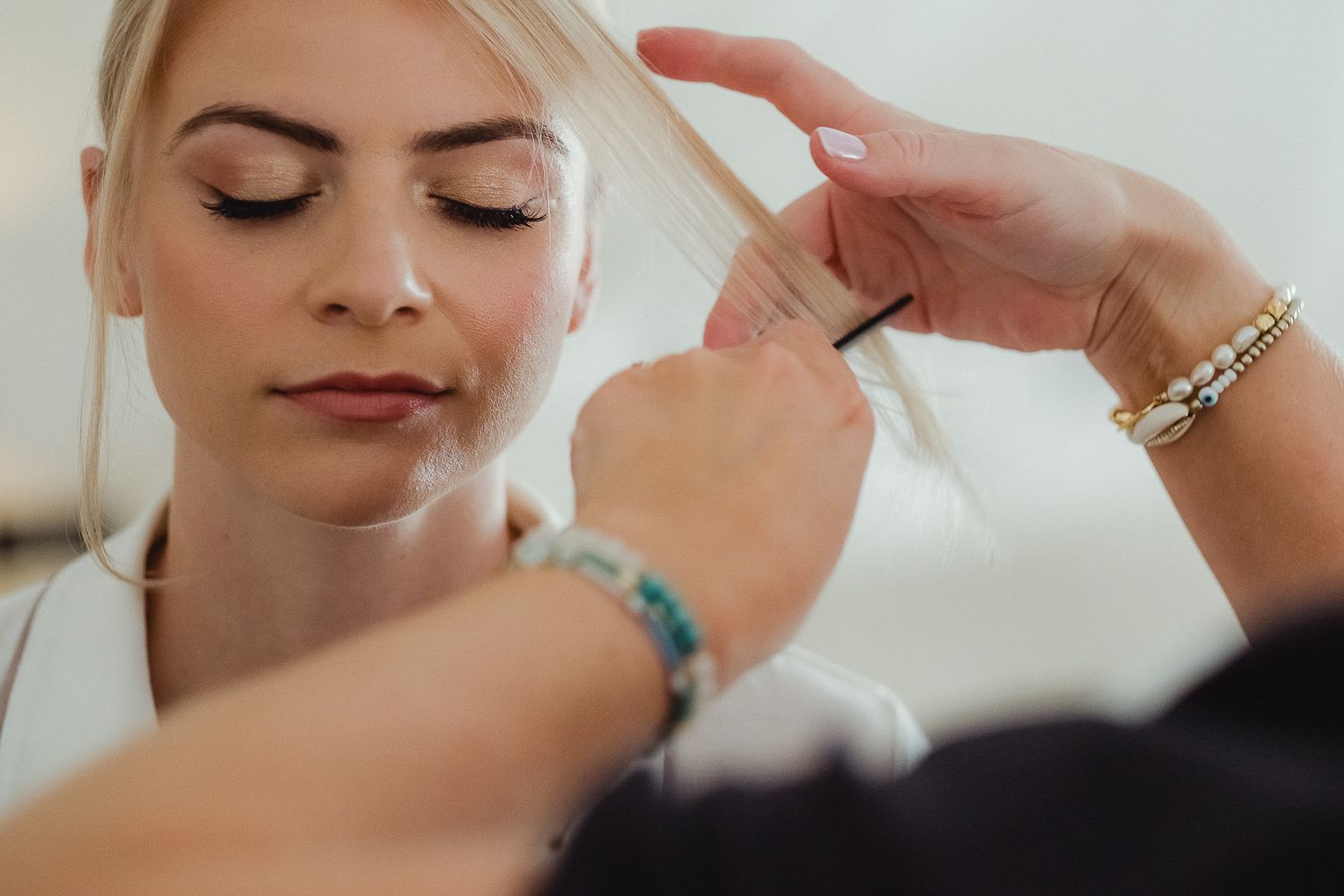 Makeup artist applies eyebrow product with precise brush strokes during professional beauty session.