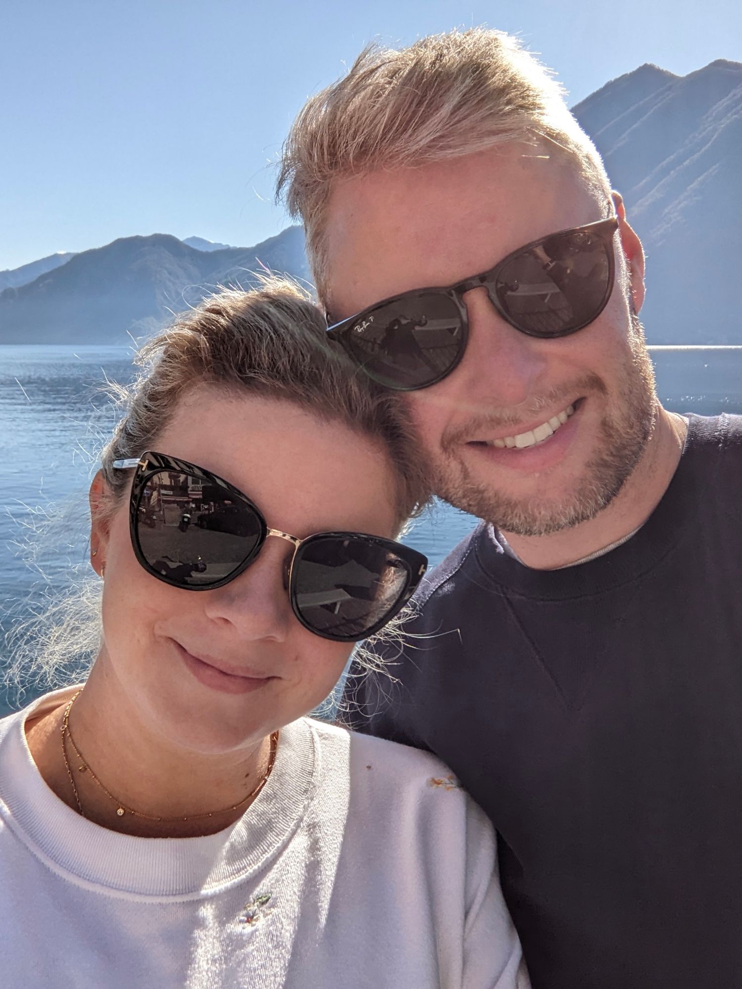 Four selfie photos taken on a boat with mountains and water in the background on a sunny day.