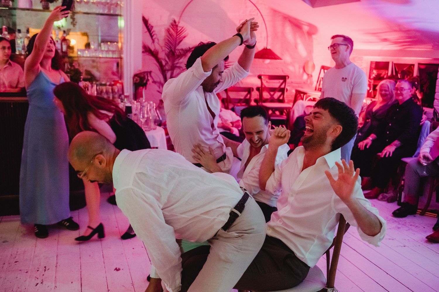 People dancing together in a pink-lit room during a lively celebration event.