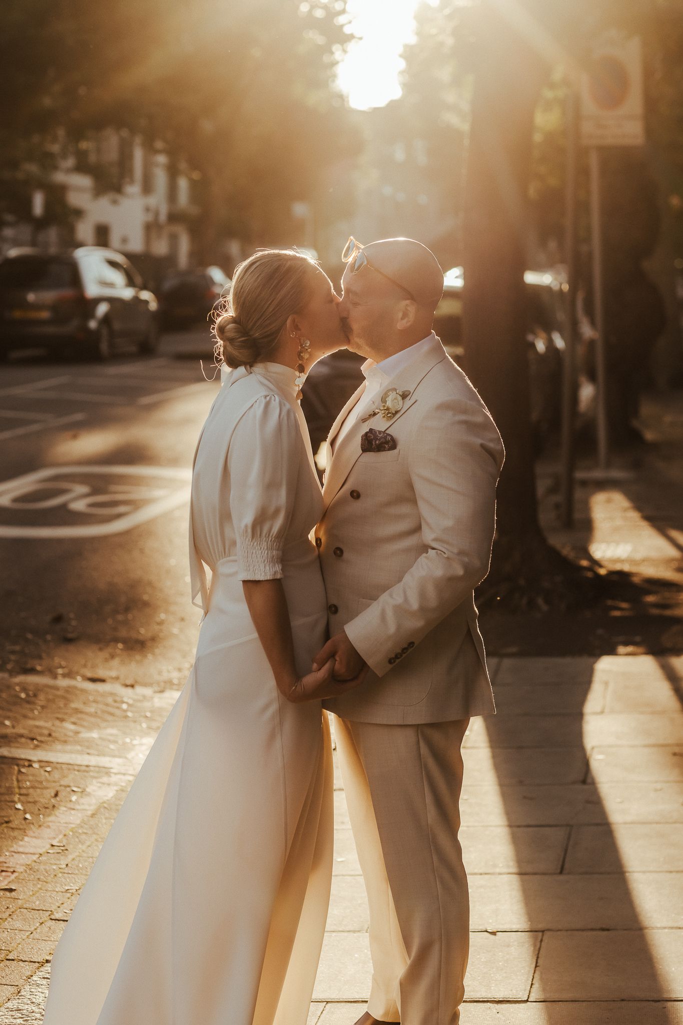 A romantic sunset wedding photograph on an urban sidewalk with beautiful golden hour lighting and long shadows.