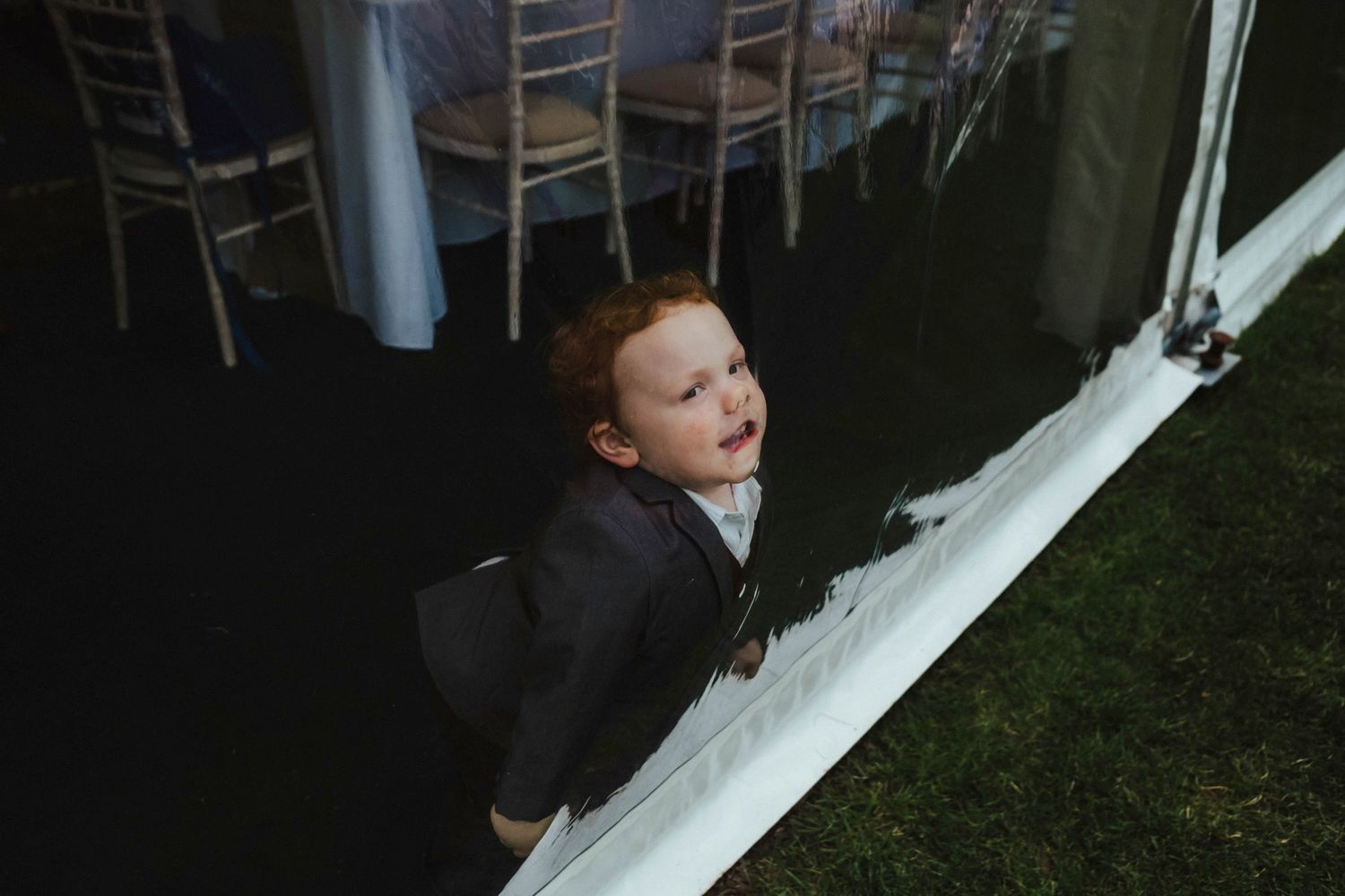 A small child peeks through white fabric at an indoor event.