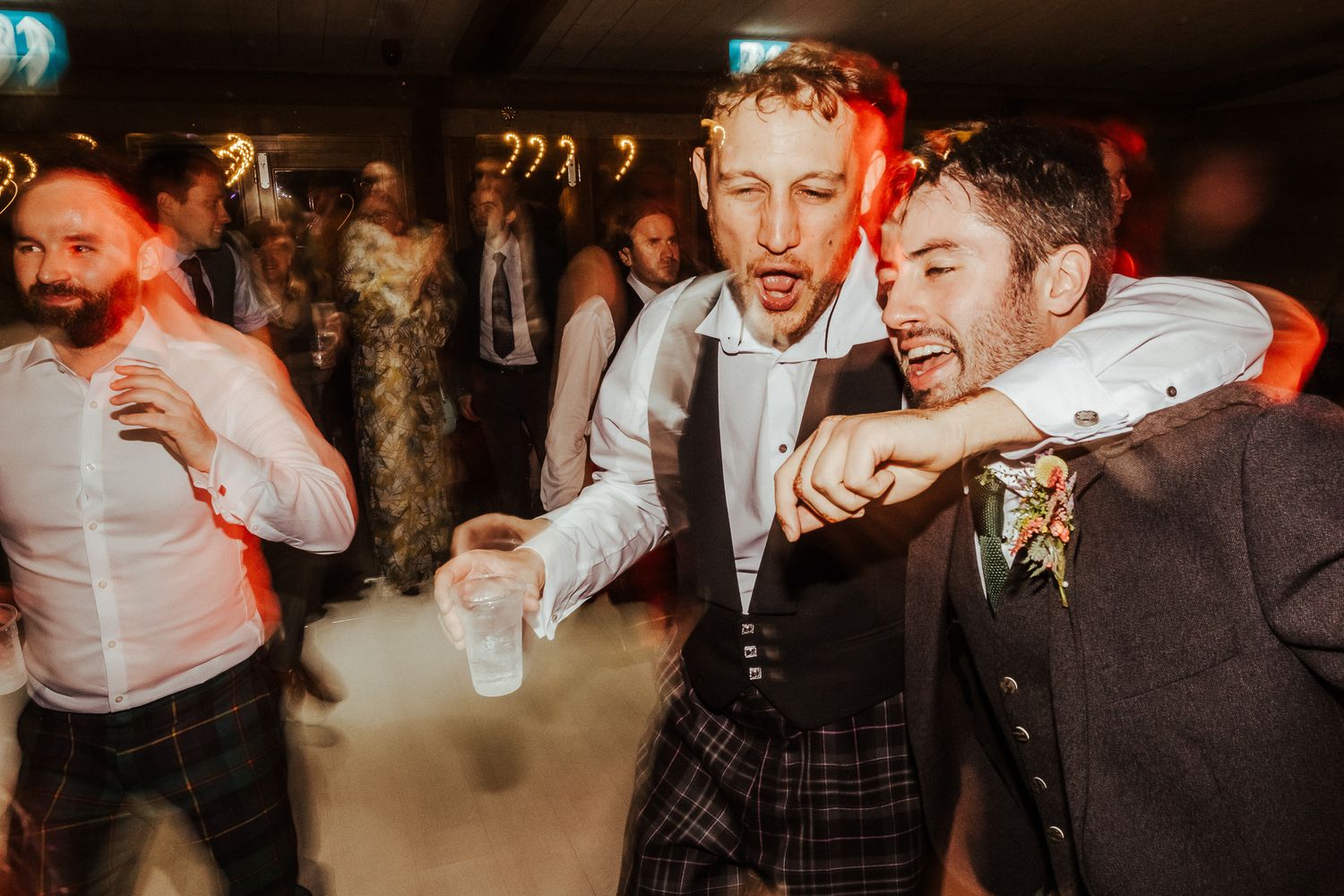 Wedding guests laughing and celebrating at a lively reception party.