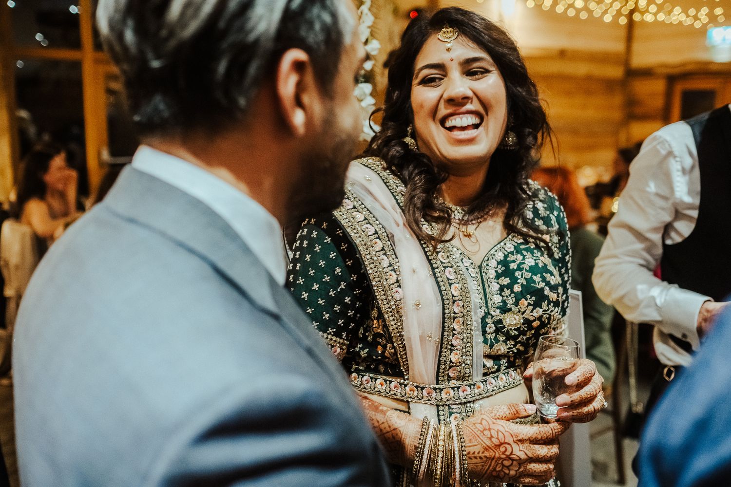 Guests dressed in traditional Indian attire share laughs during a celebration.
