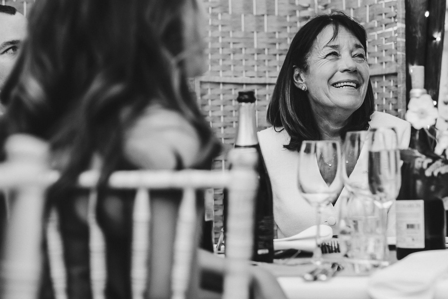 Black and white candid shots of guests enjoying themselves during wedding reception dinner.