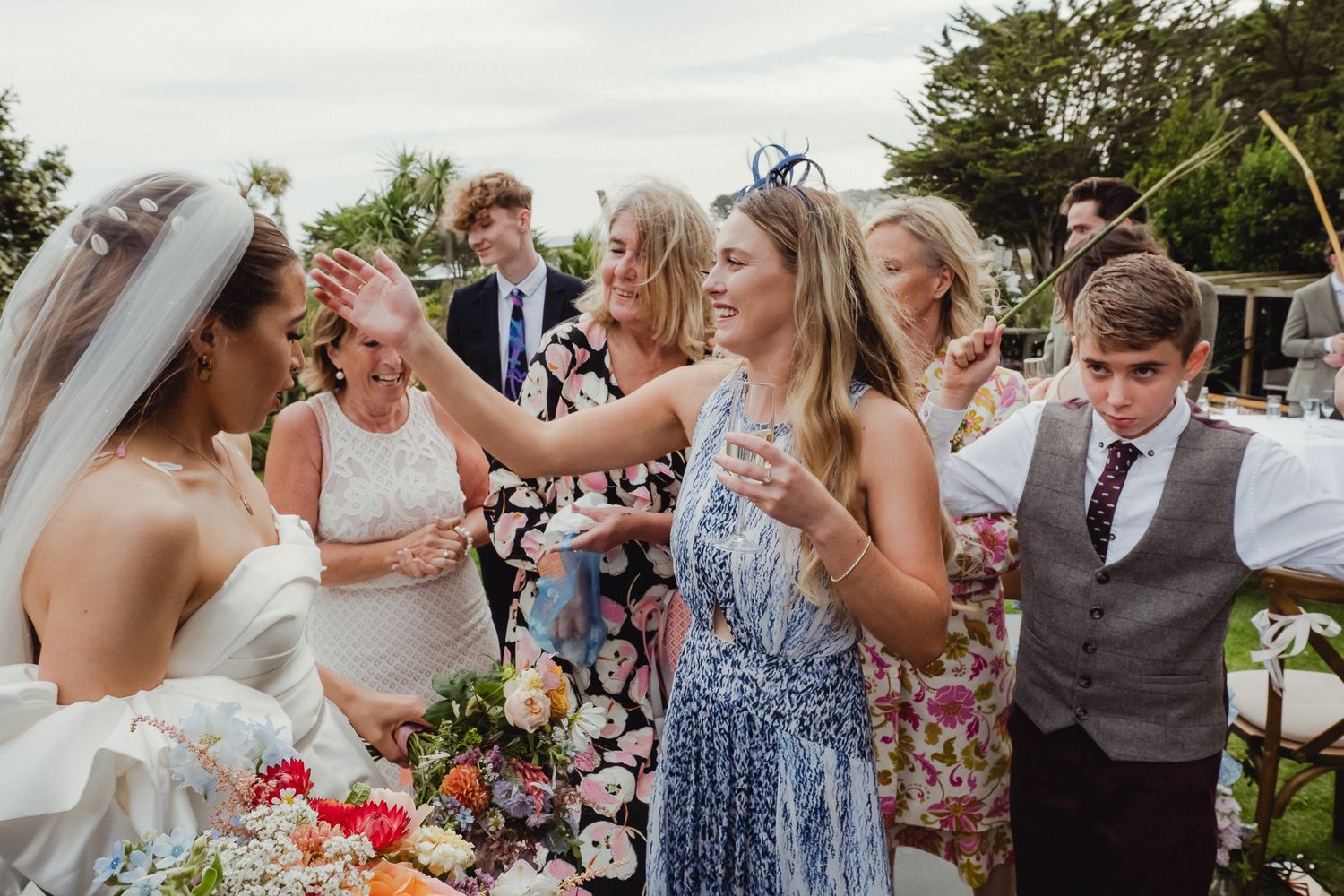 Wedding party celebrates joyfully outdoors with candid moments of dancing and laughter at a summer reception.