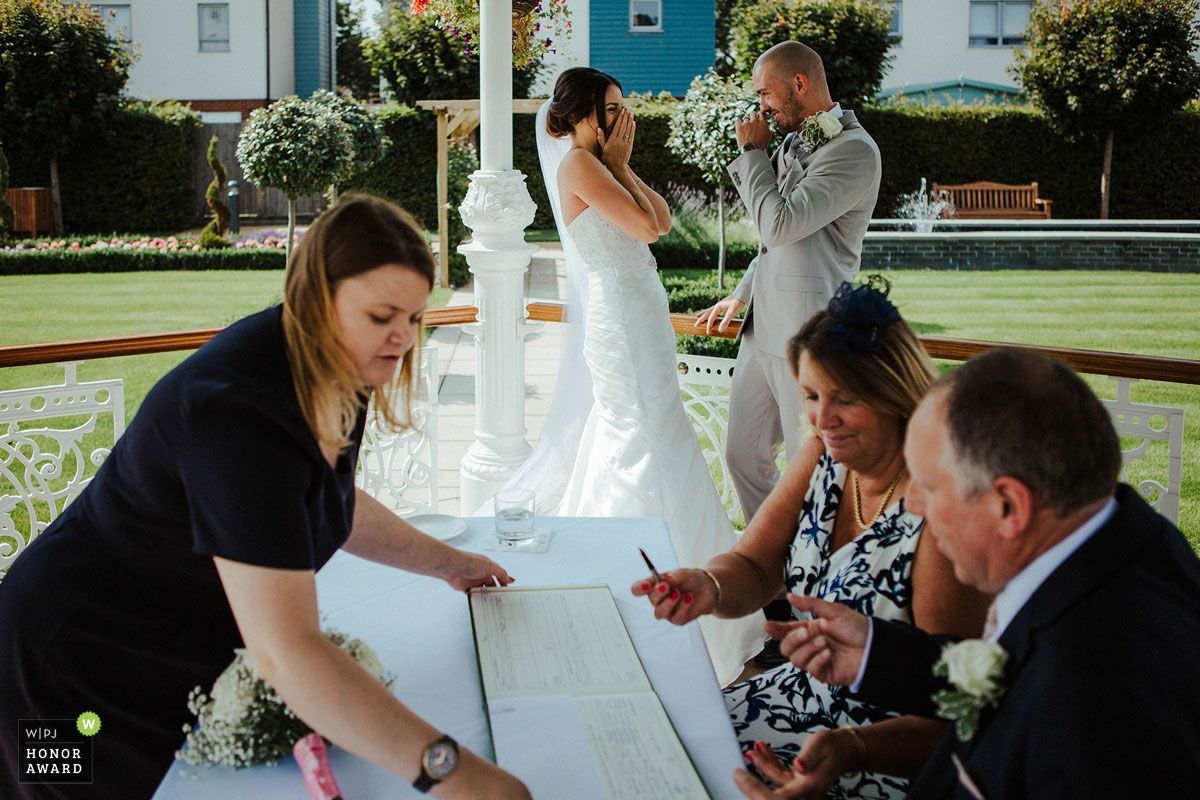 People share a lighthearted moment during an outdoor wedding ceremony on a sunny day.