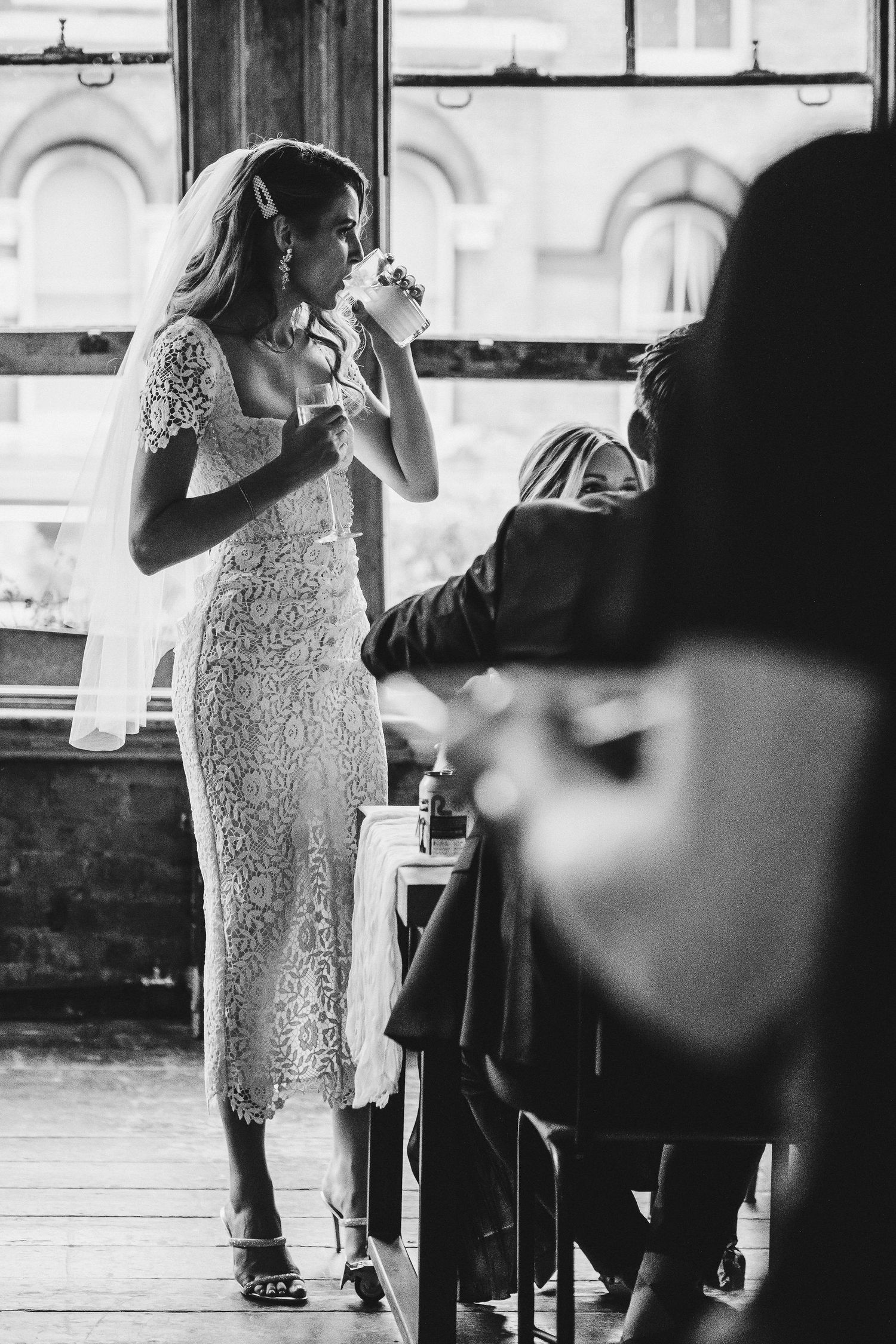 A woman in a white lace dress walks through a restaurant interior in a series of black and white photographs.