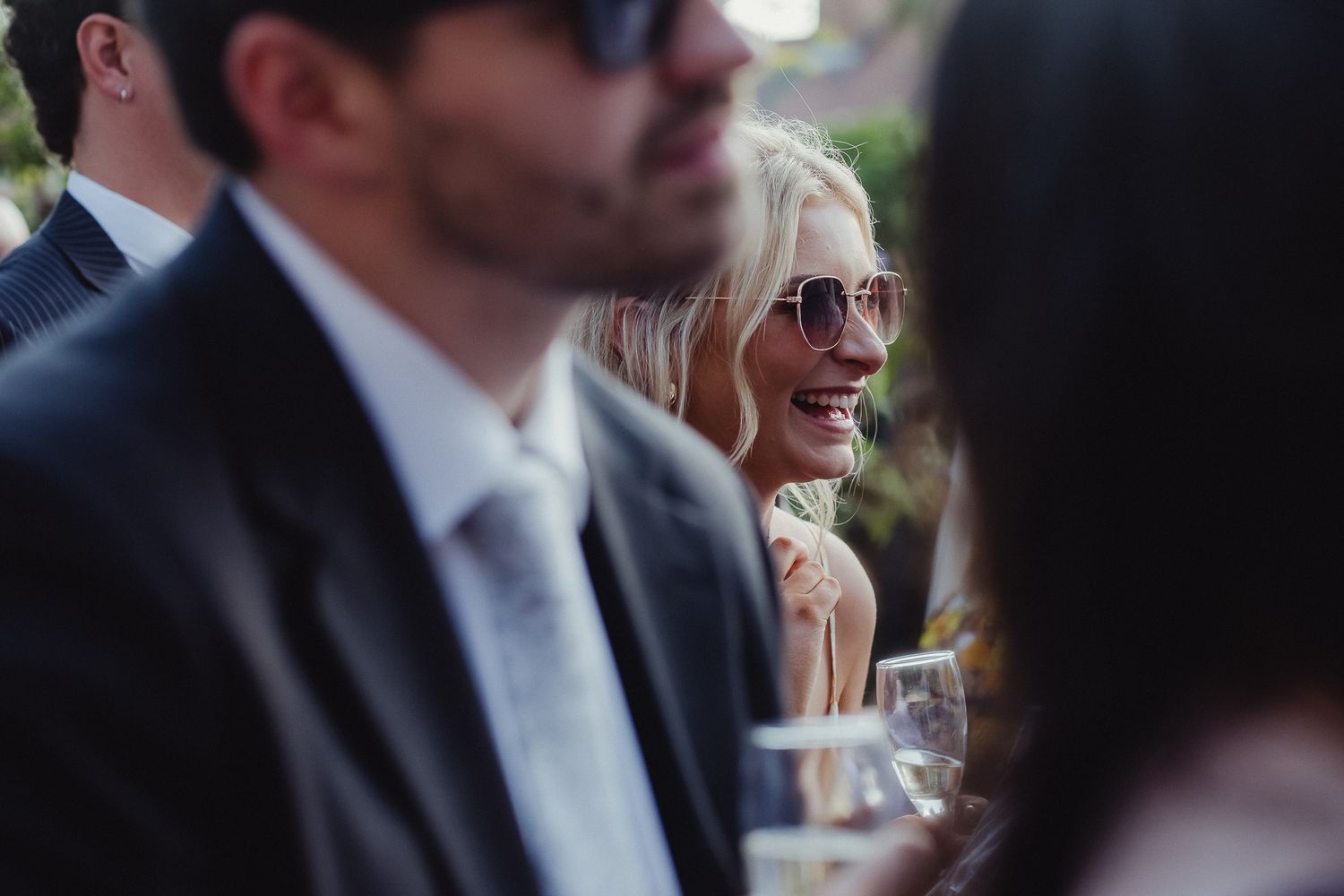 People in formal attire enjoying drinks and conversation at an elegant outdoor social gathering.