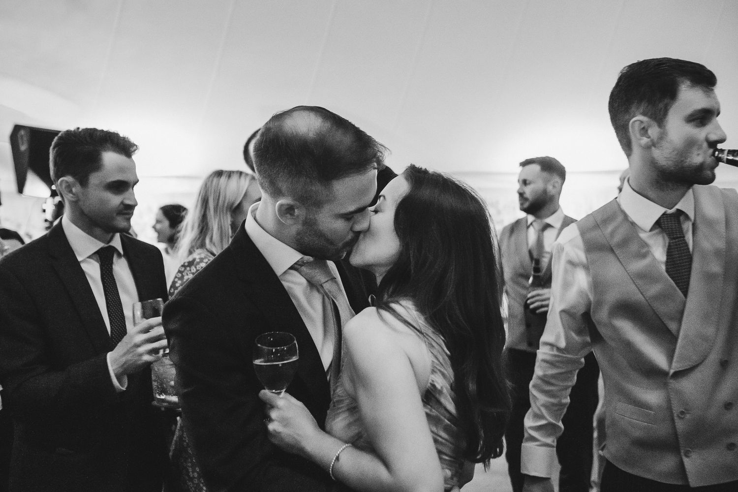 Black and white photo of wedding guests mingling and chatting during an elegant reception celebration.
