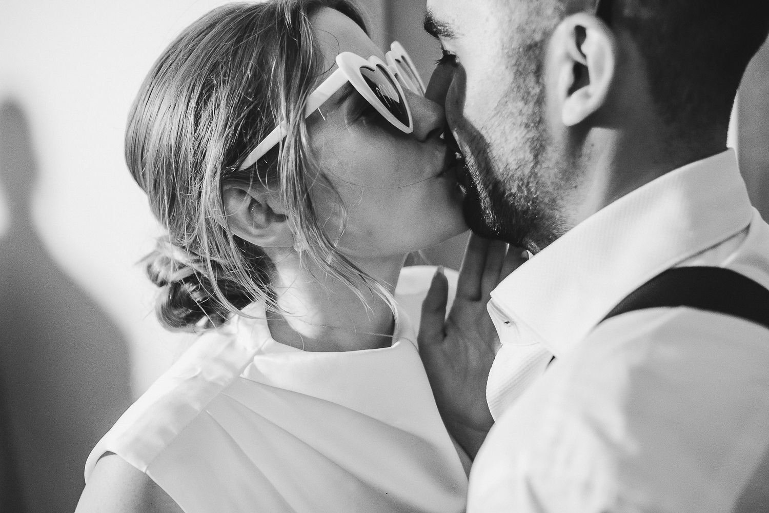 A romantic black and white photograph captures an intimate kiss between a couple in formal attire.