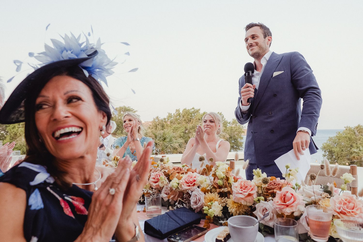 Wedding guests blowing bubbles and celebrating joyfully during an outdoor ceremony in the sunshine.
