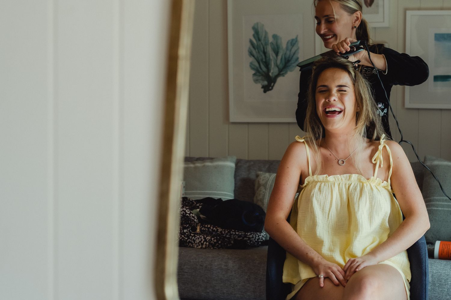 A candid moment of laughter and joy during wedding day hair styling preparations.