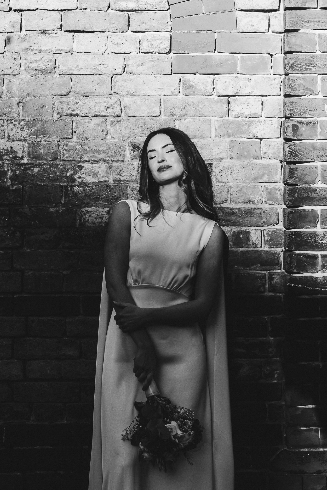 Artistic black and white portrait series against brick wall showing dramatic poses in moody lighting.