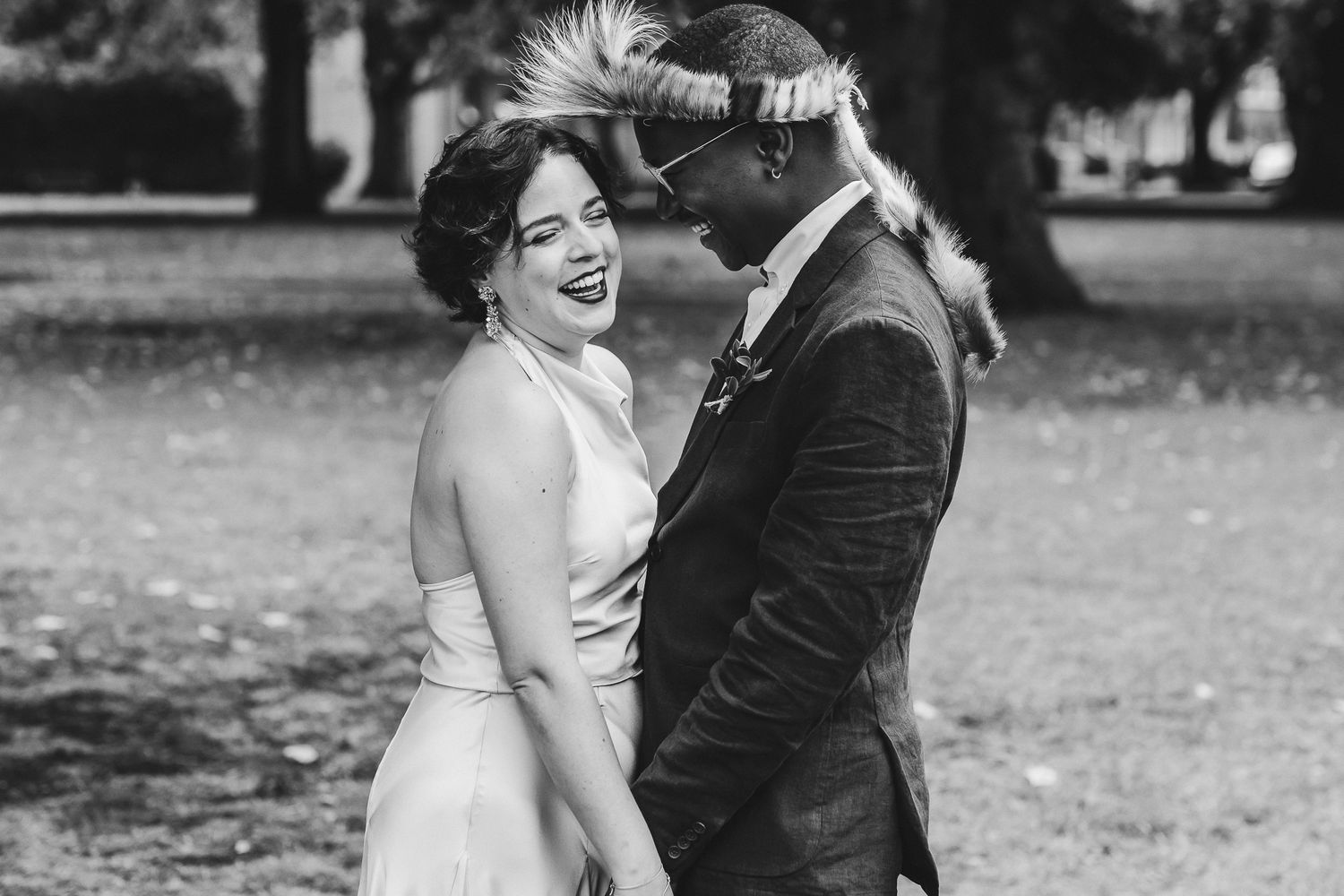 A happy couple in wedding attire share joyful candid moments in black and white photography.