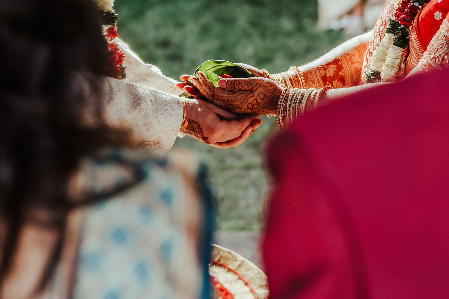 A traditional wedding ceremony moment with hands exchanging ritual items.