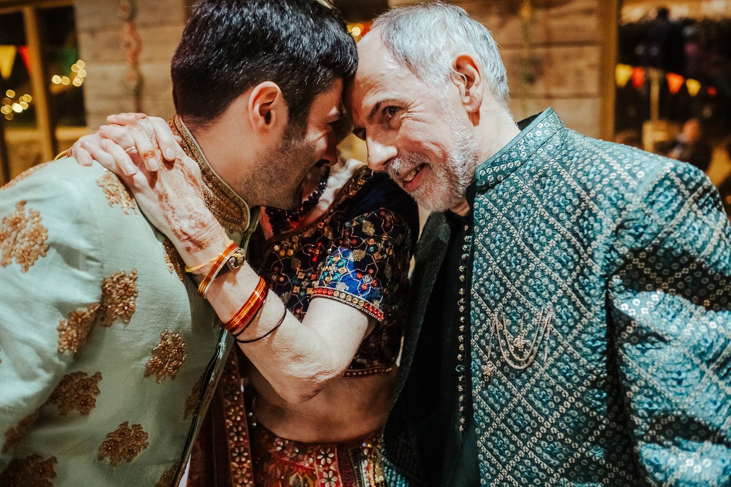 Intimate moment between guests in traditional Indian formal wear at a celebratory event.