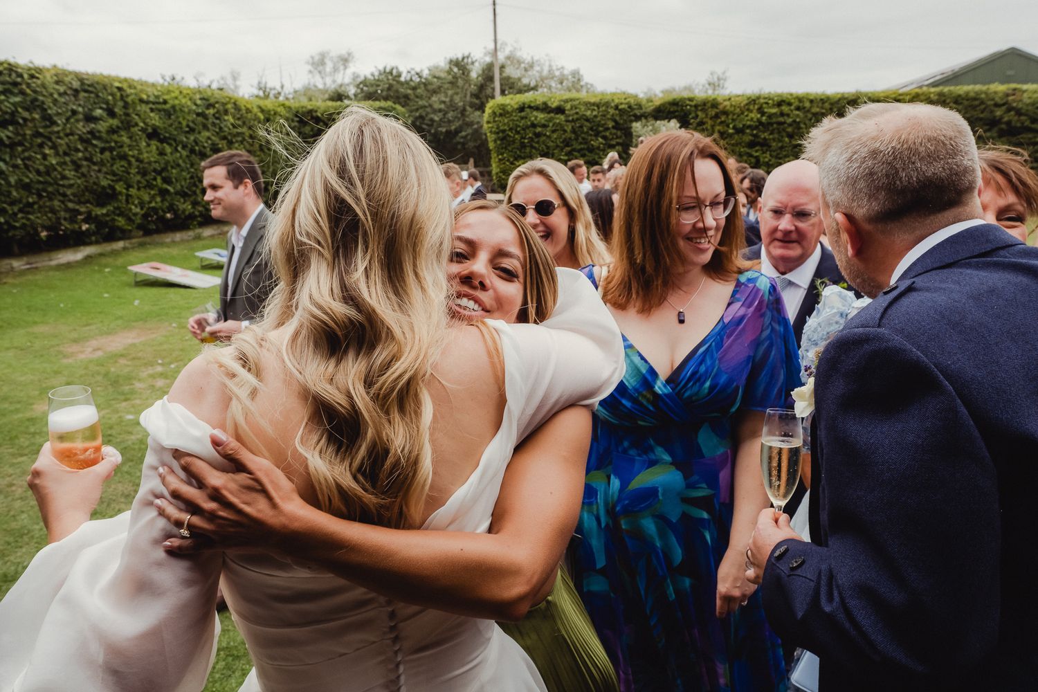 A series of candid wedding reception moments showing guests embracing and celebrating outdoors.