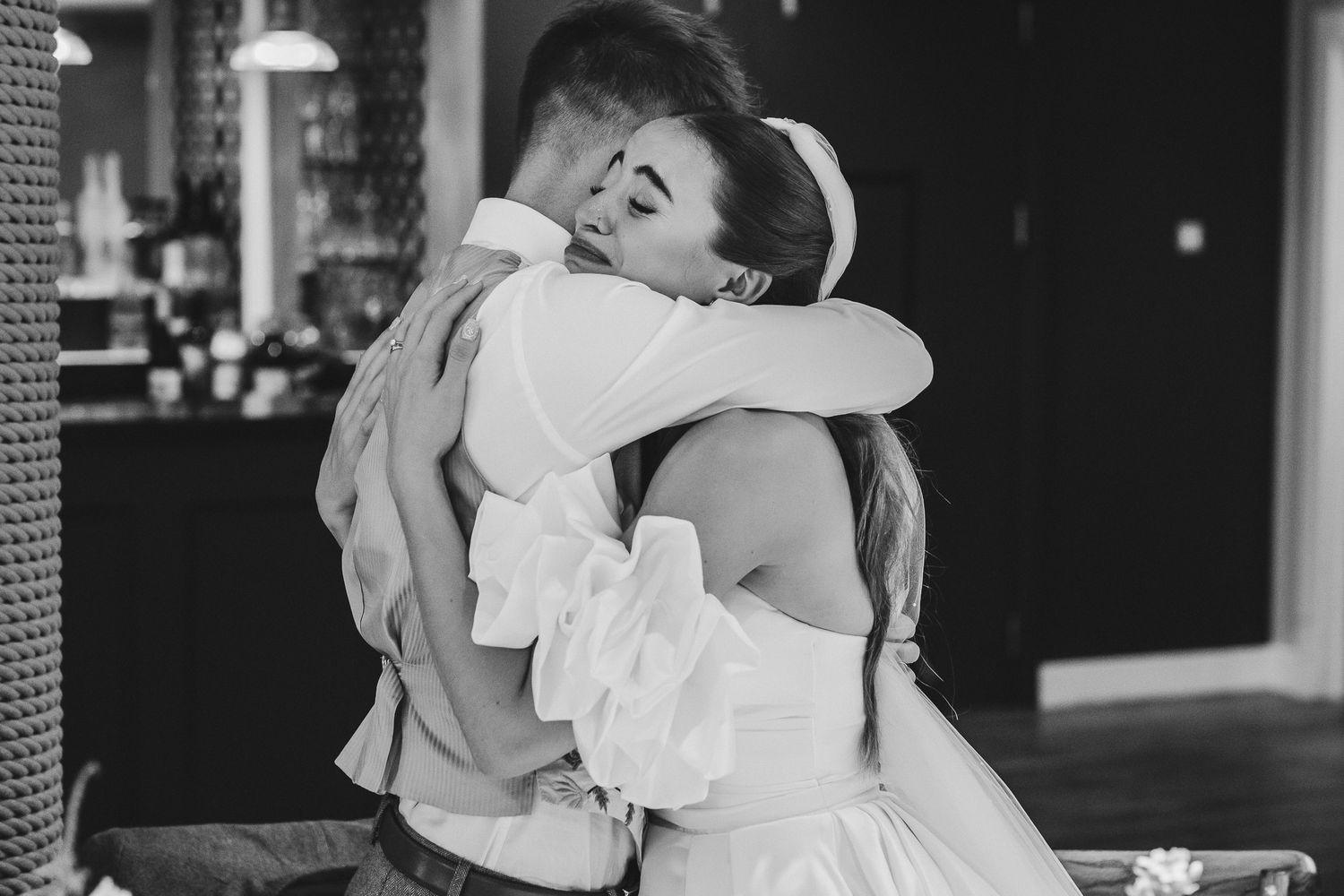Black and white photo of a couple dancing together at a wedding reception with guests in the background.