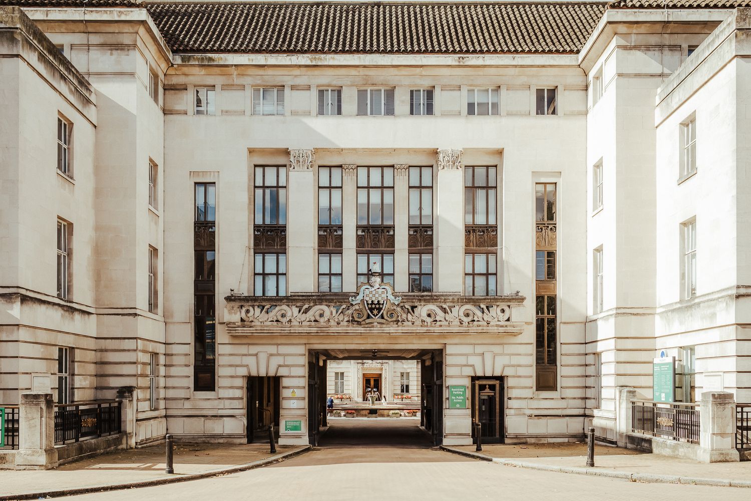 Interior architectural details of a historic building with ornate moldings, columns and archways spanning a long hallway.
