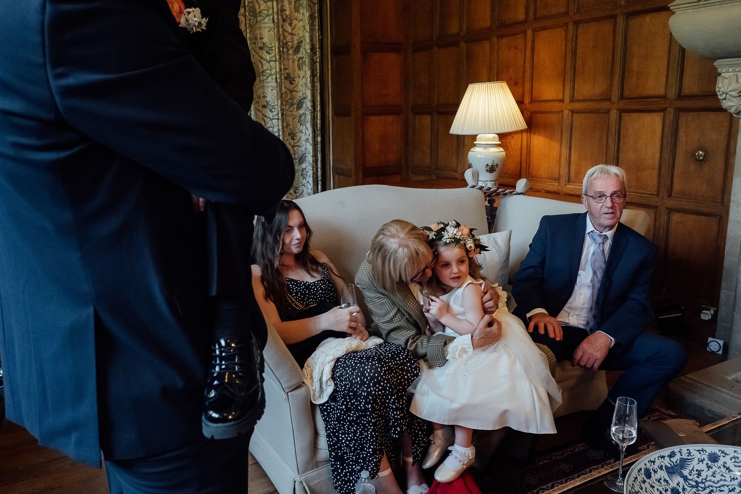 Family gathering at a wedding reception, with elderly couple and children sitting on a sofa in an elegant room.
