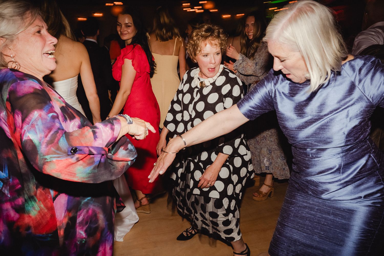 A group of people dancing at a lively party with colored lights and festive atmosphere.