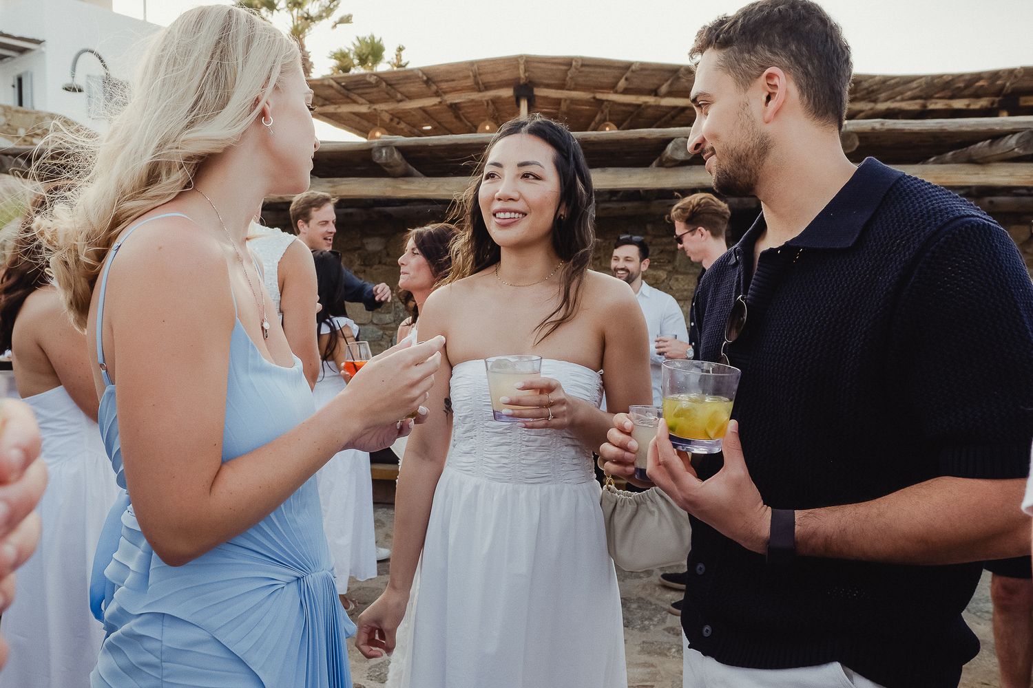 Wedding guests enjoying drinks and conversation during an outdoor reception celebration at rustic venue.