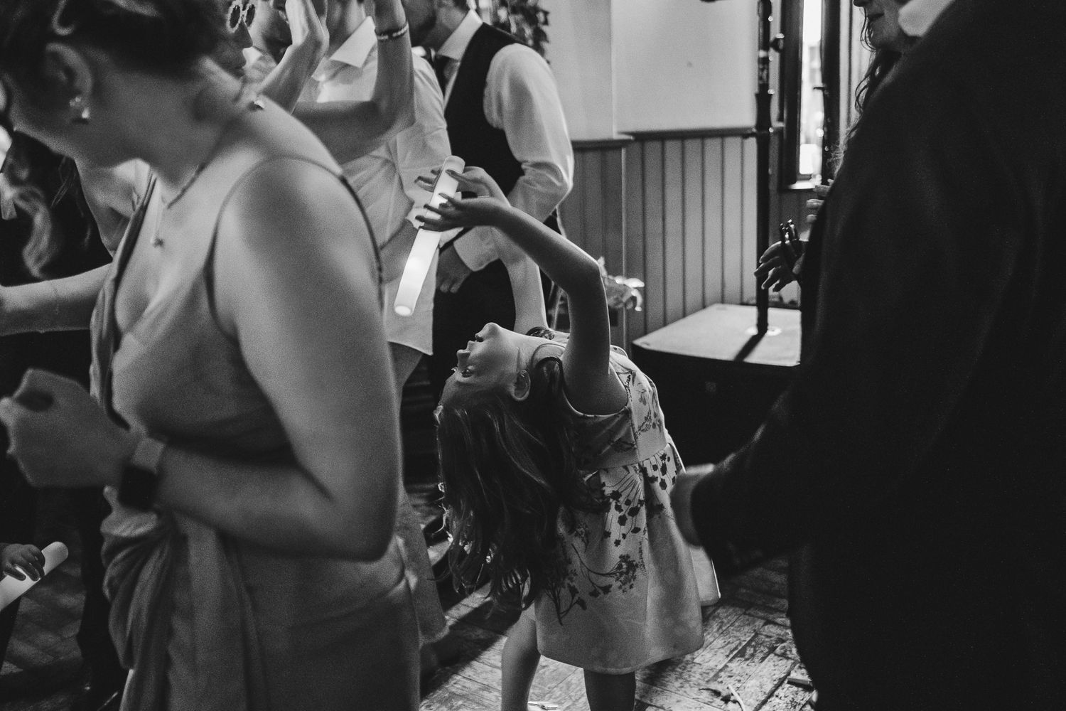 A black and white photo shows people dancing together at what appears to be a wedding reception or party.
