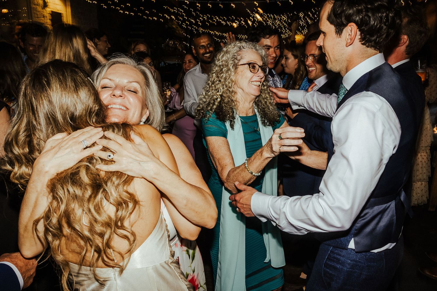Couples dance together at a dimly lit wedding reception party with joyful expressions.