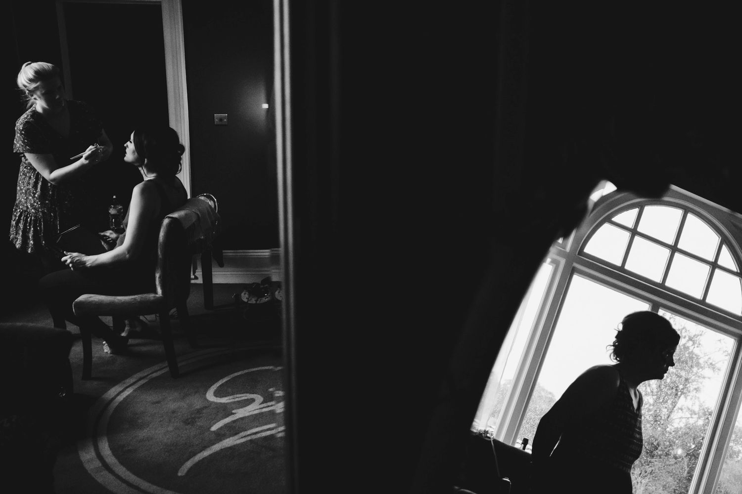 Dramatic black and white photo showing wedding preparations through doorways and windows.