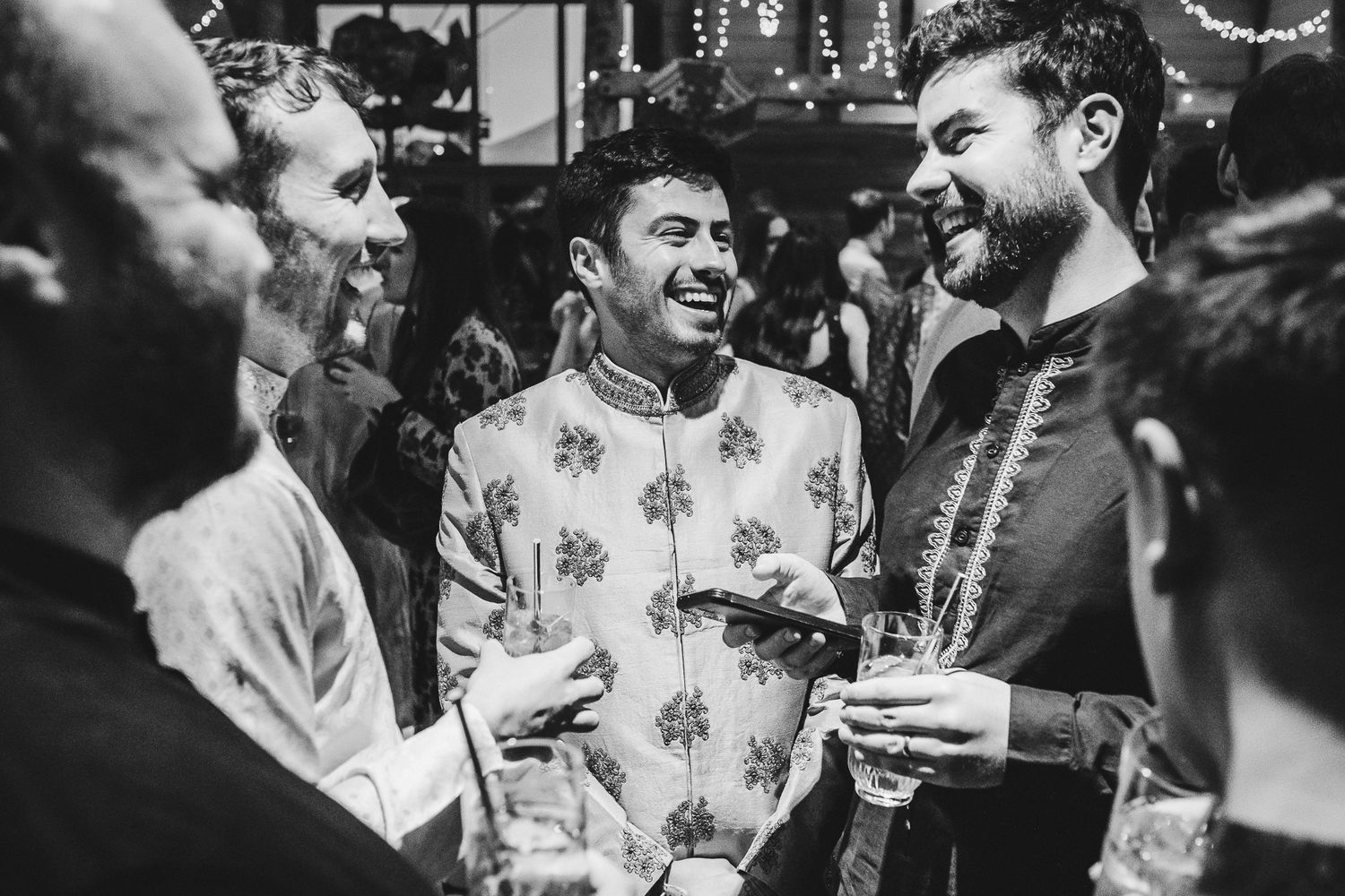 A black and white photo captures joyful celebration moments at an indoor party.
