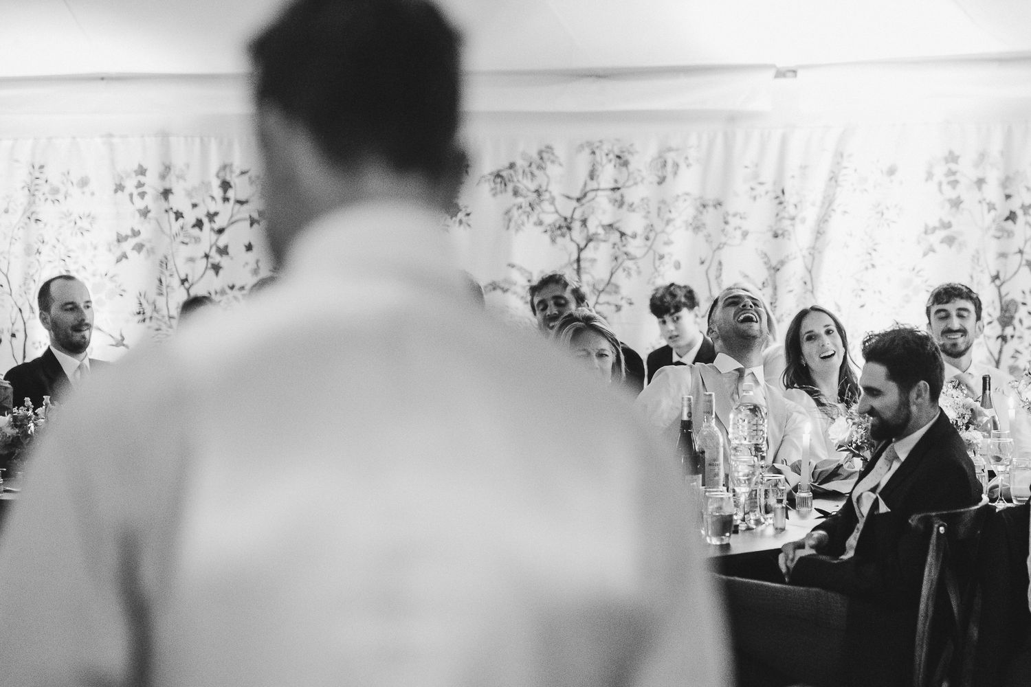 Black and white photo of wedding guests mingling and socializing during a reception in an elegant venue.