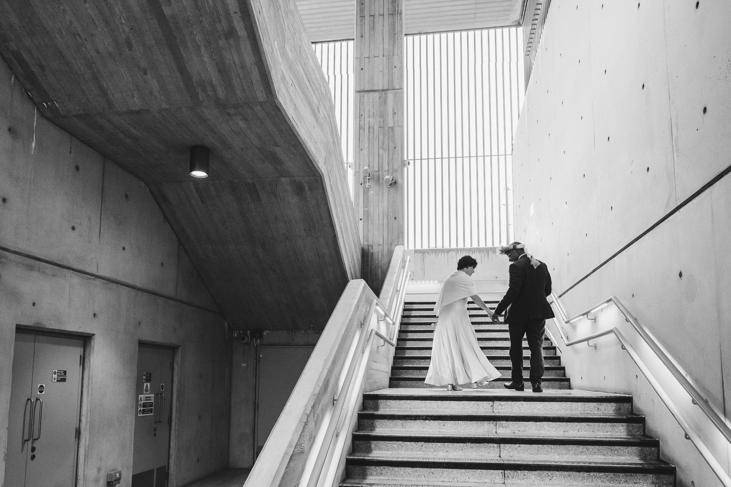 Modern architectural interior with concrete walls and ascending staircase featuring dramatic lighting and shadows.