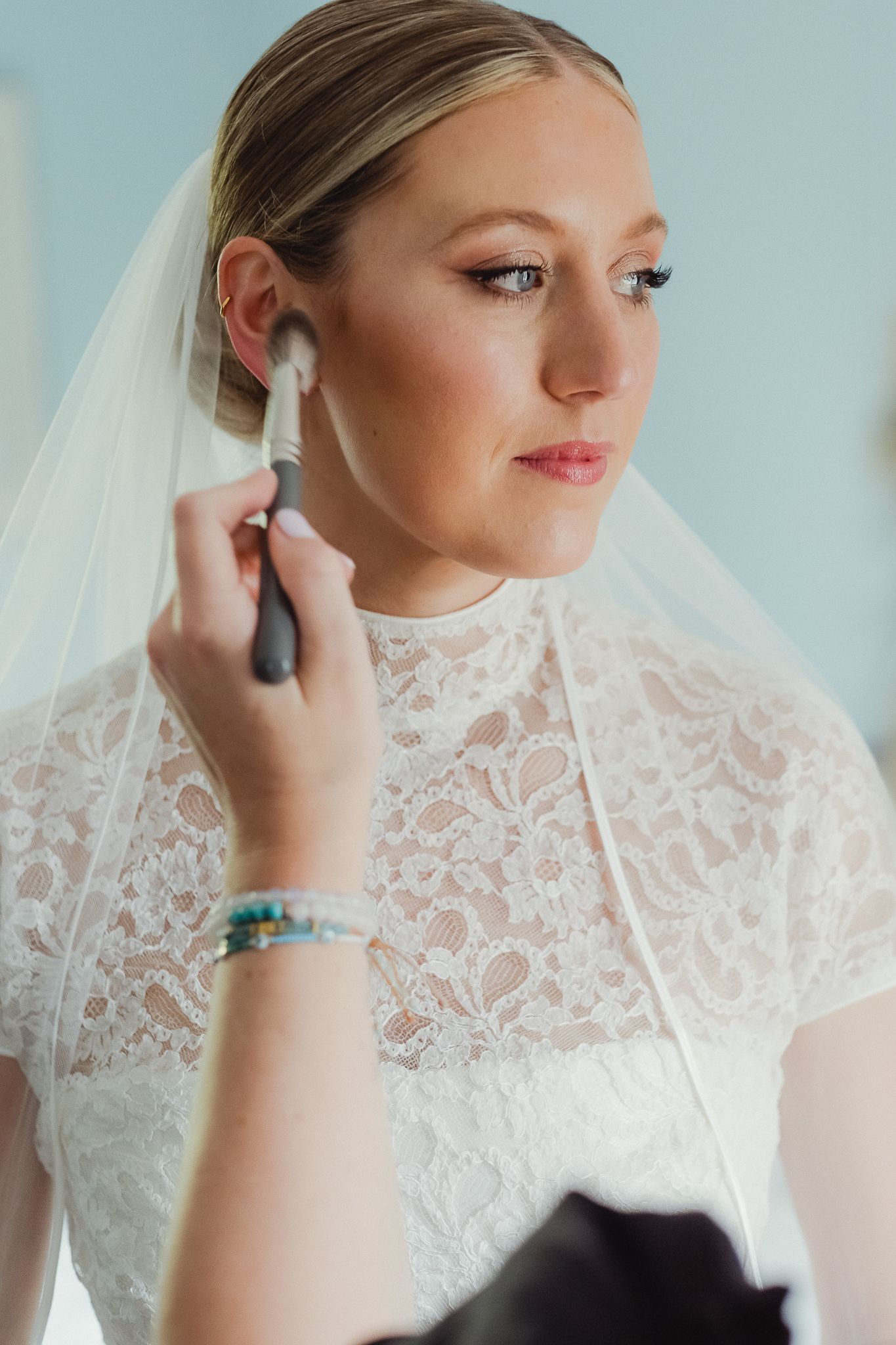 A series of bridal portraits showing delicate lace detailing and elegant jewelry as final touches are applied.