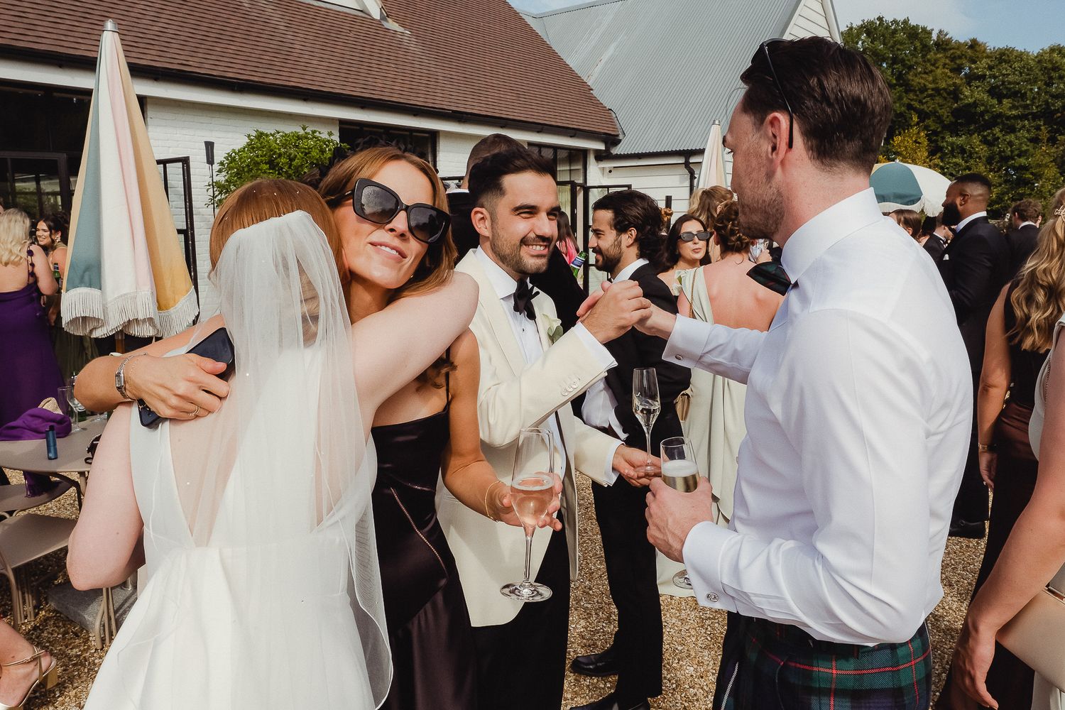 Wedding guests dance and embrace during a lively outdoor celebration at a rustic venue.
