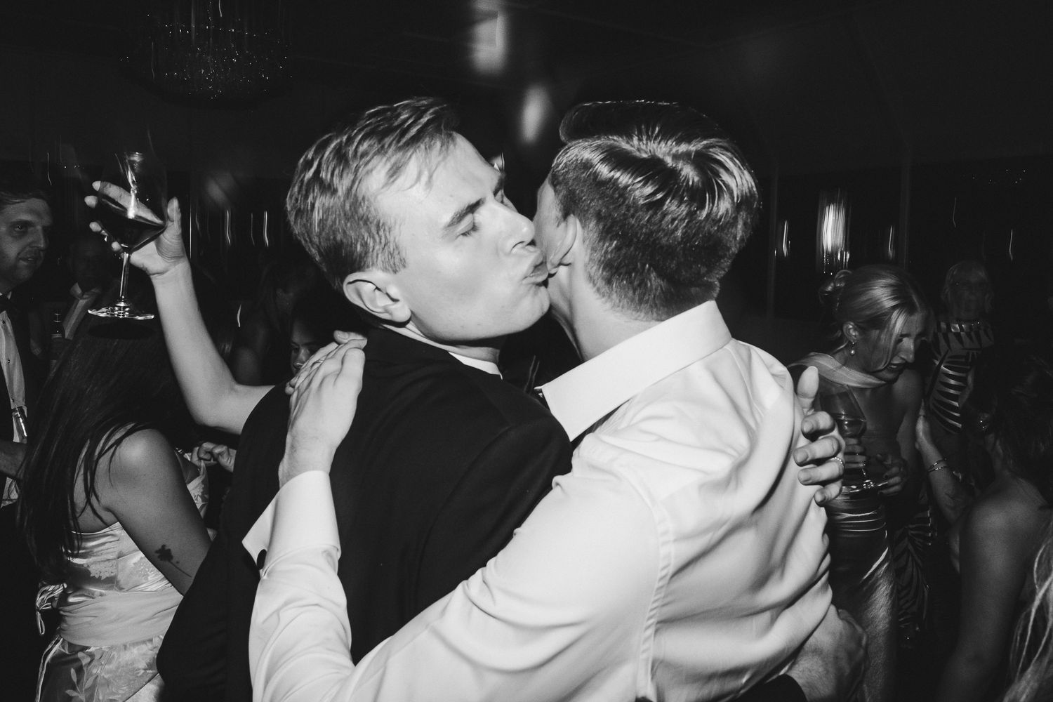 A group of people dancing and celebrating at a dimly lit party or nightclub venue.